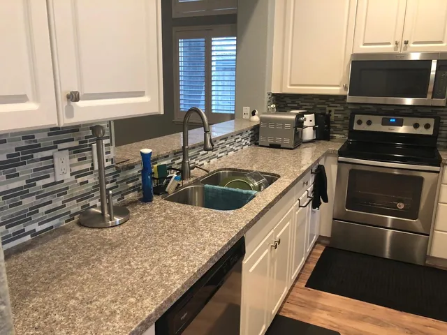 a kitchen with granite countertop a sink and a stove top oven