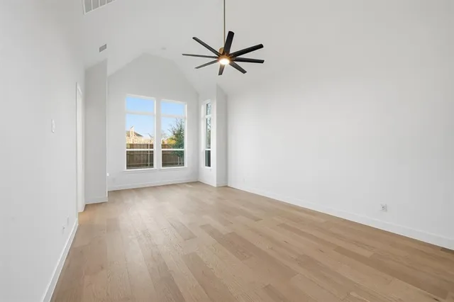 an empty room with wooden floor fan and windows