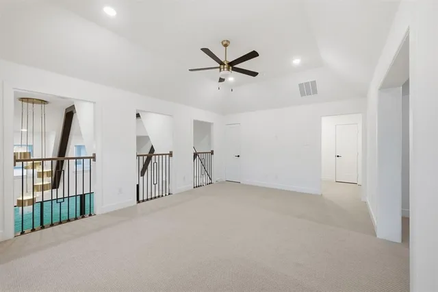 an empty room with ceiling fan and windows
