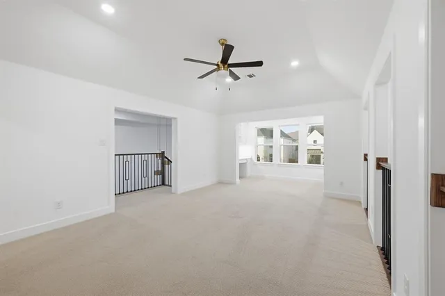an empty room with chandelier fan and windows