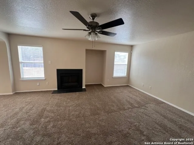 an empty room with windows and ceiling fan