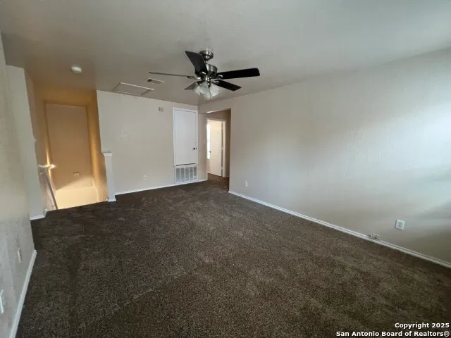 an empty room with a ceiling fan and window