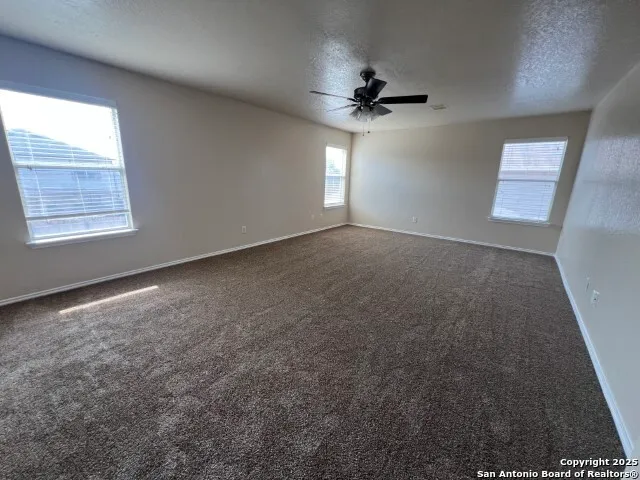 an empty room with windows and fan