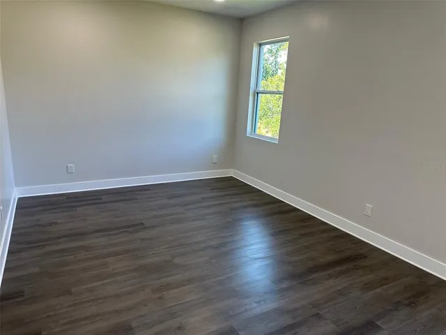 a view of an empty room with wooden floor and closet