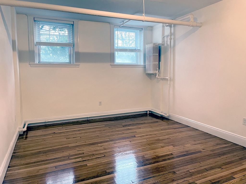 15 Thatcher Street, Unit B Brookline, MA 02446 - Photo 4 of 8 a view of an empty room with wooden floor and a window