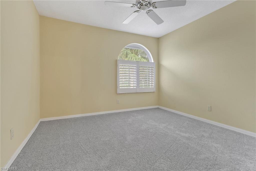 875 New Waterford Drive, Unit T201 Naples, FL 34104 - Photo 13 of 25 an empty room with windows and chandelier fan
