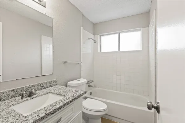 a bathroom with a granite countertop toilet a sink and a bathtub