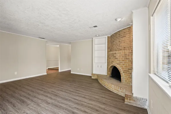 a view of empty room with fireplace and wooden floor