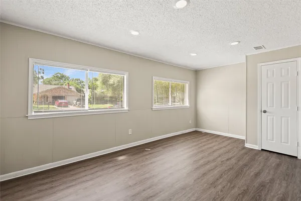 a view of empty room with wooden floor and window