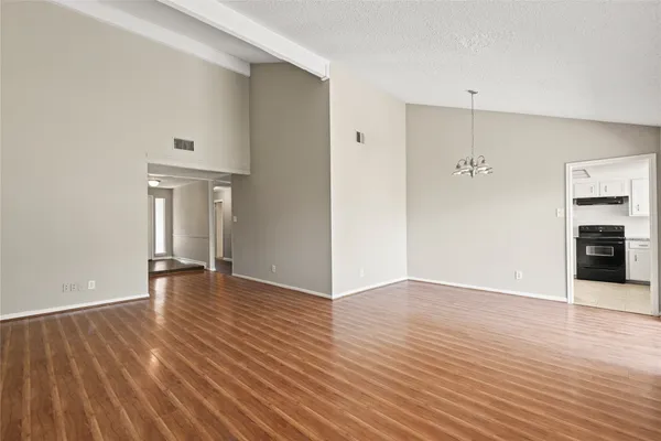 an empty room with wooden floor fireplace and windows