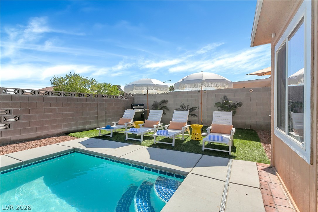 101 Beaver Ridge Avenue North Las Vegas, NV 89031 - Photo 35 of 42 A tranquil backyard oasis features a glistening pool, inviting lounge chairs, and lush green accents.