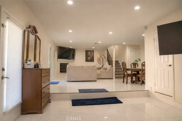 a living room with stainless steel appliances furniture a rug and a flat screen tv