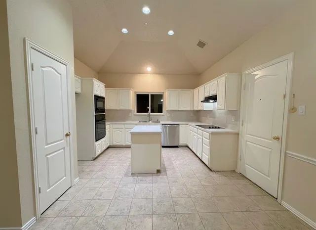 a large white kitchen with white cabinets and stainless steel appliances