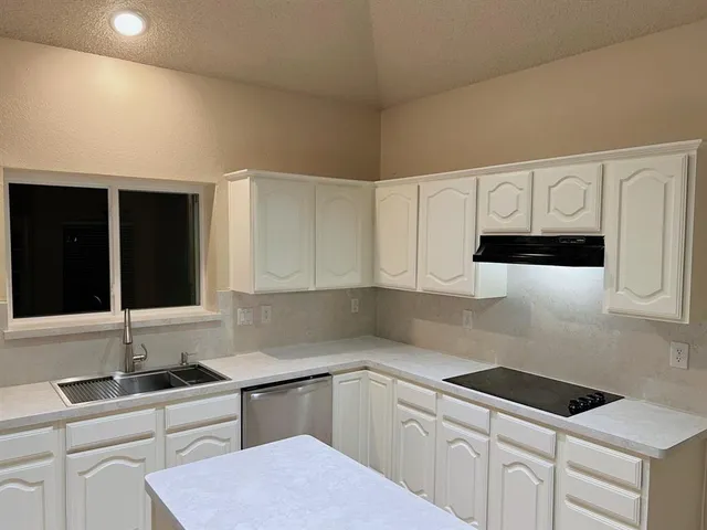 a kitchen with granite countertop white cabinets and sink