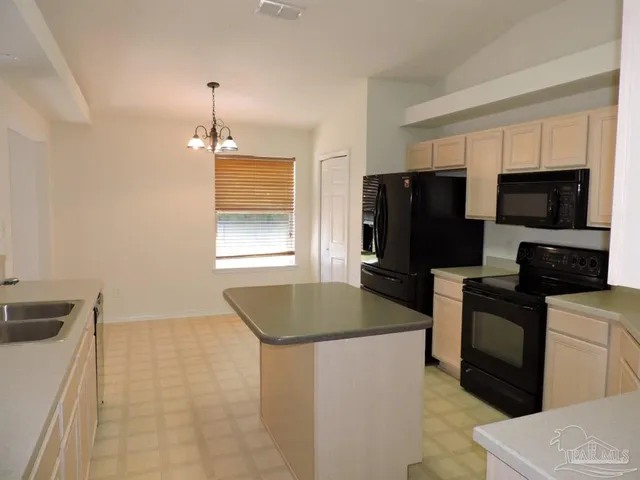a kitchen with granite countertop a refrigerator and a stove top oven