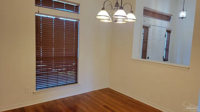 an empty room with wooden floor chandelier and entryway