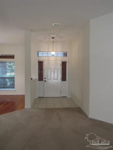 an empty room with chandelier fan and windows