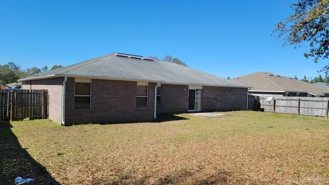 a view of a backyard with wooden fence and a large tree
