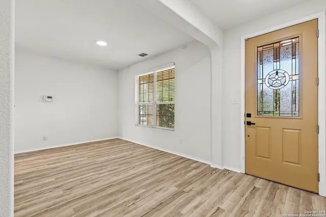 a view of an empty room with a window and wooden floor