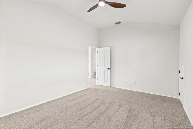 an empty room with a ceiling fan and wooden floor