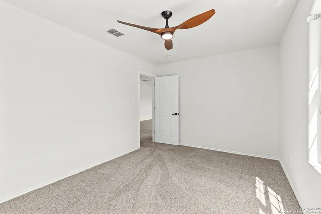 an empty room with ceiling fan and window