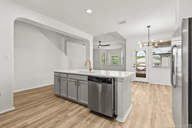 a kitchen with stainless steel appliances granite countertop a sink a stove and a wooden floors