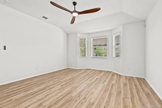 a view of empty room with wooden floor and fan