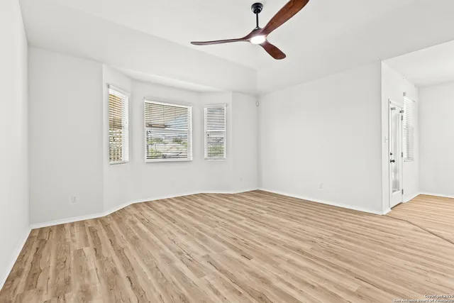 a view of empty room with wooden floor and fan
