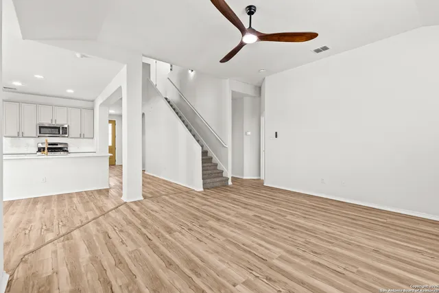 a view of a kitchen with wooden floor electronic appliances and stairs