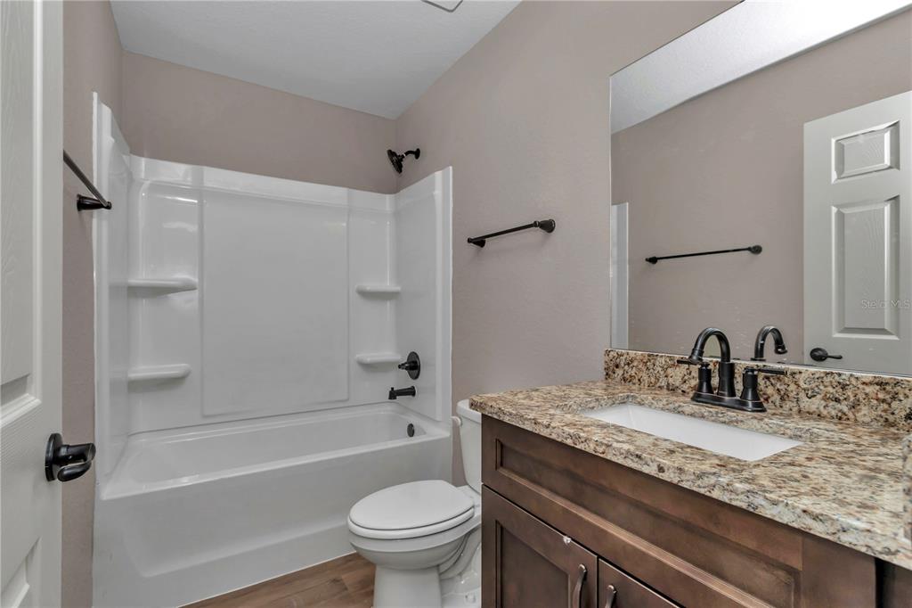 12841 Southwest 83rd Terrace Ocala, FL 34473 - Photo 27 of 31 a bathroom with a granite countertop toilet sink and bathtub