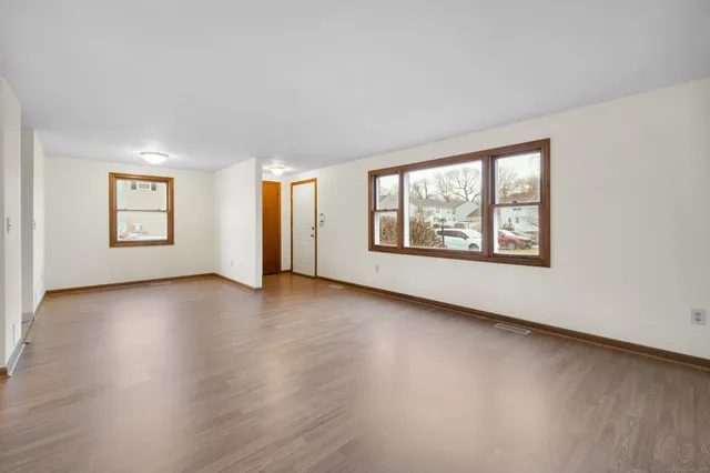 a view of an empty room with a window and wooden floor