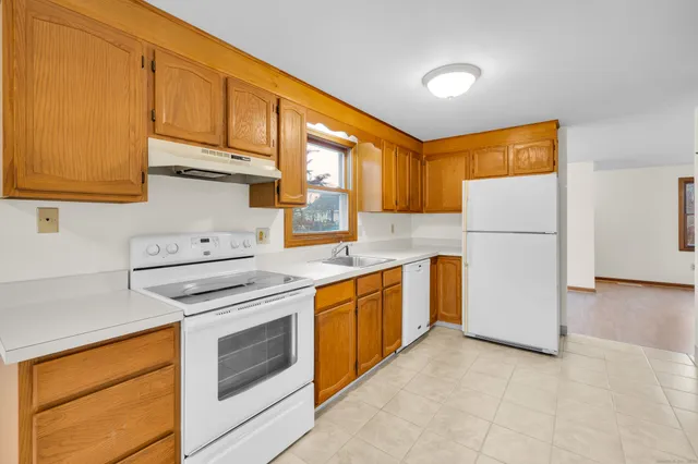 a kitchen with stainless steel appliances granite countertop a refrigerator a stove a sink and a white cabinets