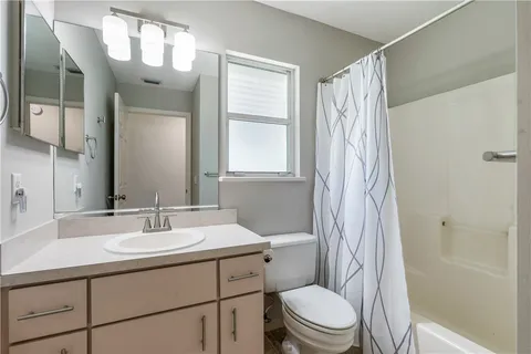 a bathroom with a sink a toilet a mirror a vanity and shower