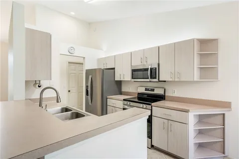 a kitchen with stainless steel appliances a refrigerator stove and white cabinets
