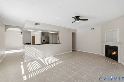 an empty room with wooden floor fan and windows