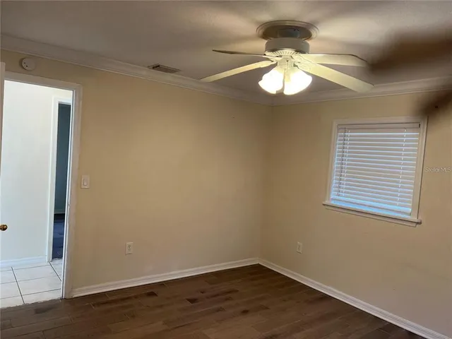 a view of an empty room with wooden floor and a window