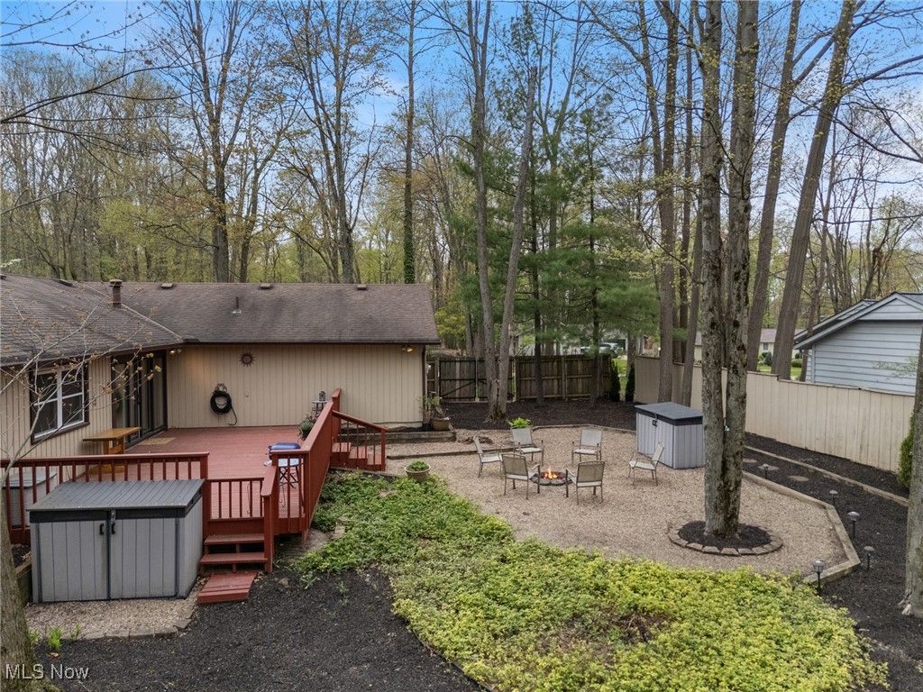 17800 Falling Leaves Road Strongsville, OH 44136 - Photo 29 of 39 View of yard featuring a deck, a fenced backyard, a storage shed, an outdoor fire pit, and an outbuilding