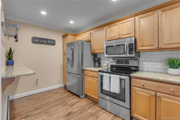 a kitchen with stainless steel appliances granite countertop a refrigerator a stove a sink and white cabinets with wooden floor