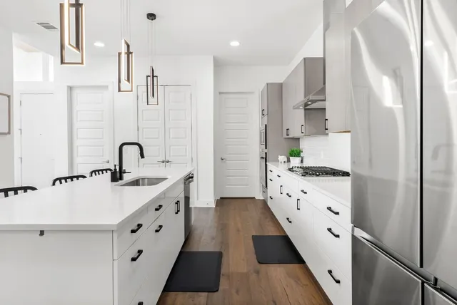 a large white kitchen with sink a refrigerator and white cabinets