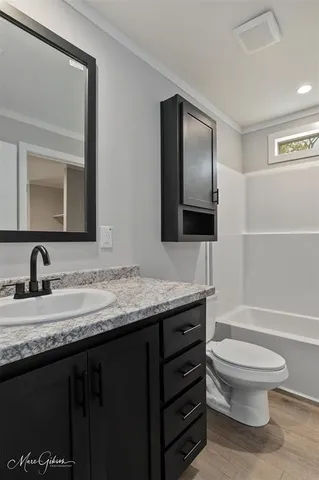 a bathroom with a granite countertop toilet a sink and a mirror