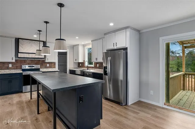 a kitchen with stainless steel appliances granite countertop a refrigerator a sink dishwasher a stove and a refrigerator with wooden floor