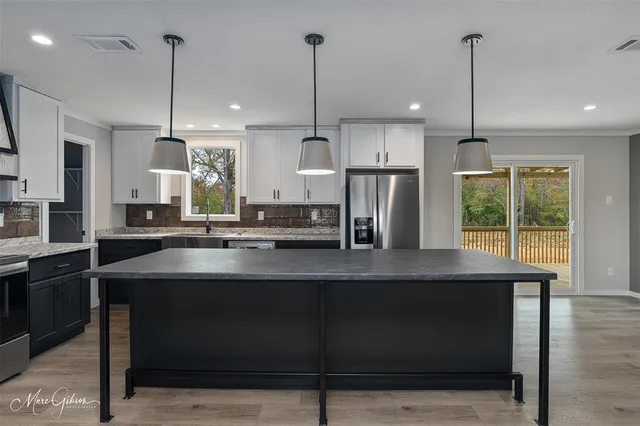 a kitchen with kitchen island stainless steel appliances a sink a center island and a wooden floor