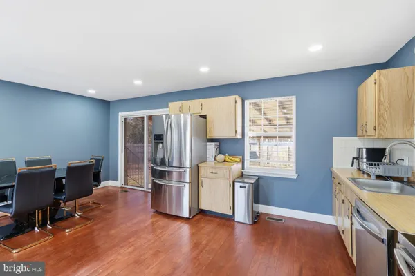 a kitchen with stainless steel appliances a stove a sink a refrigerator cabinets and wooden floor