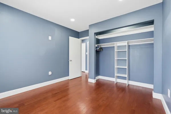 a view of an empty room with wooden floor and closet