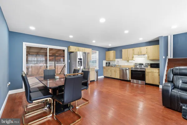 a living room with couches and kitchen view with wooden floor