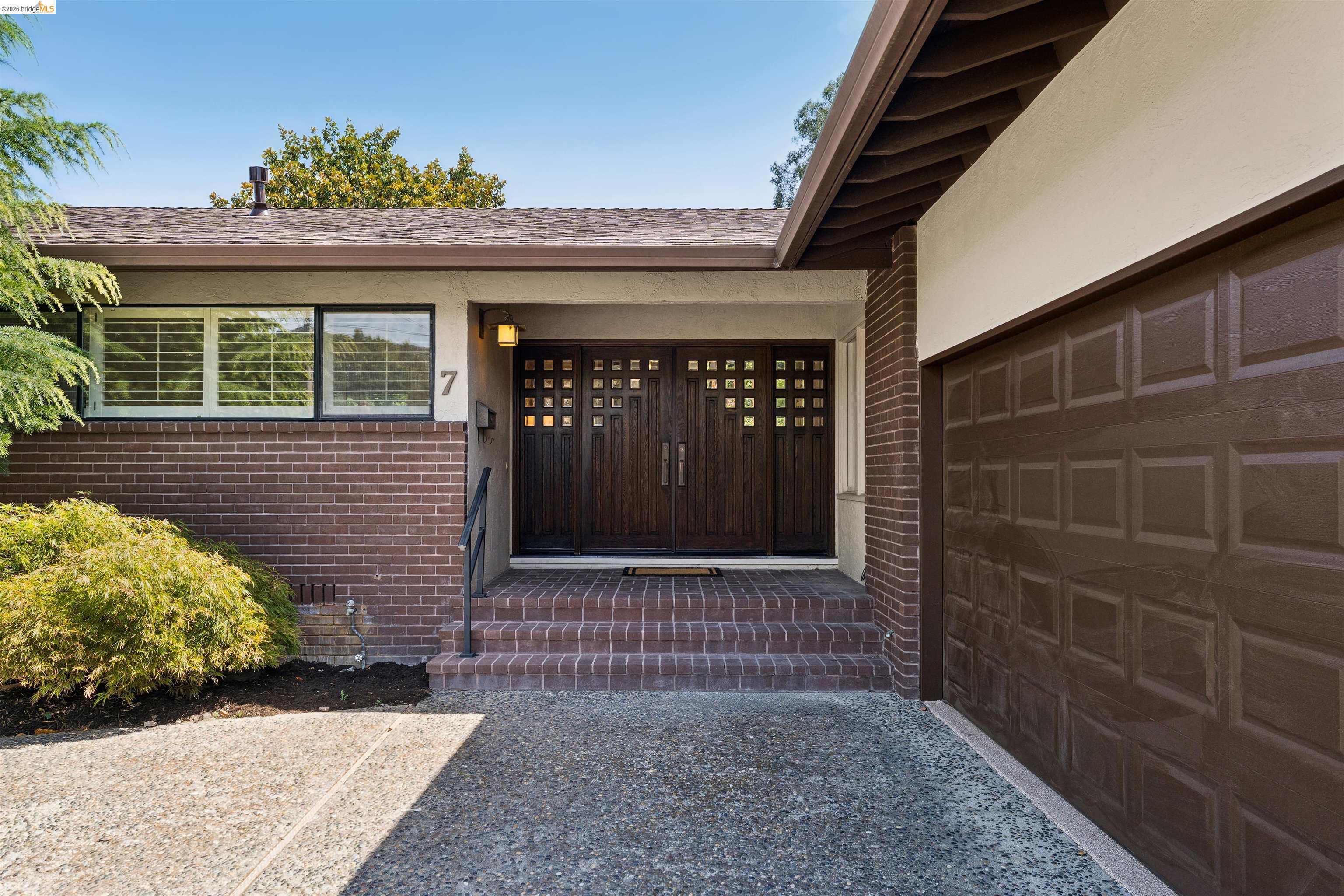 7 Jo Lin Court El Sobrante, CA 94803 - Photo 19 of 99 Brick facade with exposed aggregate concrete driveway and a brown panel garage door