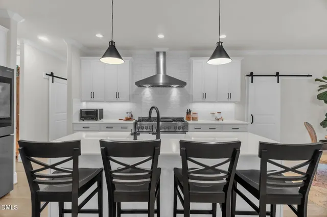 a kitchen with stainless steel appliances a dining table chairs and white cabinets