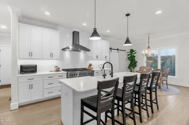 a kitchen with stainless steel appliances a dining table chairs and white cabinets