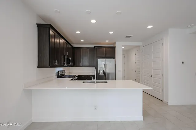 a view of kitchen island a sink a counter top space and stainless steel appliances