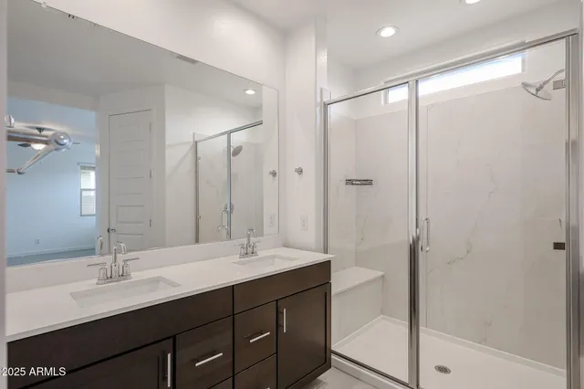 a bathroom with a double vanity sink mirror and shower